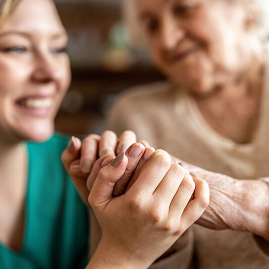 volunteer-guardian-holding-hands-with-senior-woman